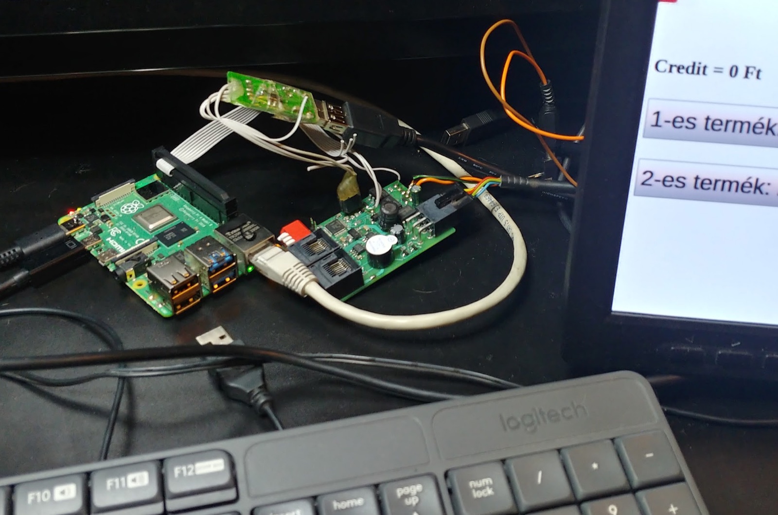 An early vending machine prototype: a Raspberry Pi, two add‑on boards, a touchscreen, a keyboard and a tangle of wires